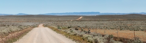 dirt road through plains going towards hills - Australian Stock Image