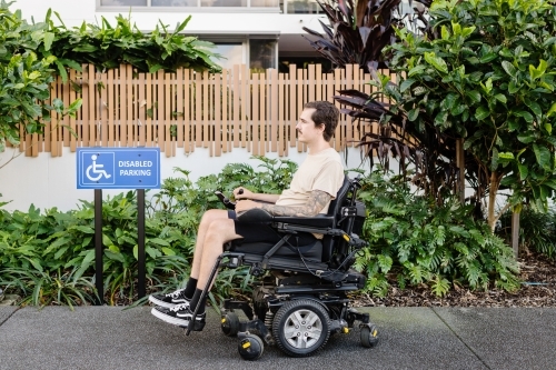disabled man in motorised wheelchair, in carpark - Australian Stock Image