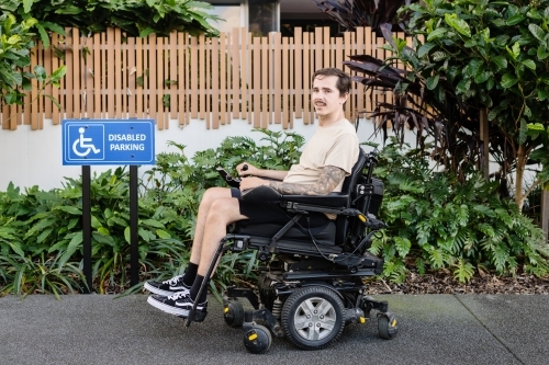 disabled man in motorised wheelchair, in carpark - Australian Stock Image