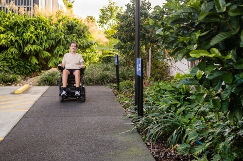 disabled man in motorised wheelchair, in carpark - Australian Stock Image