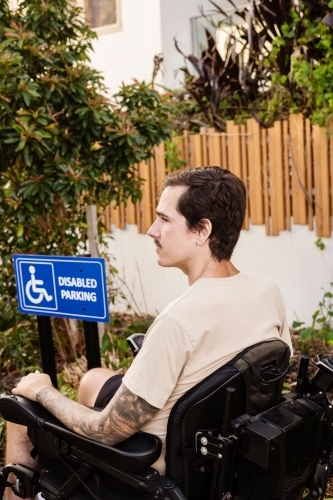 disabled man in motorised wheelchair, in carpark