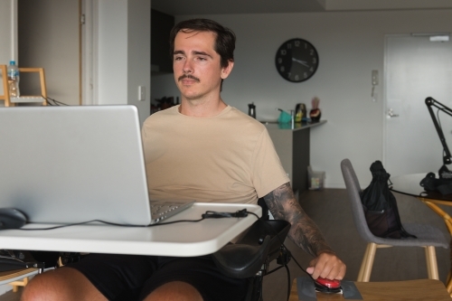 disabled man using computer, with special adaptive devices - Australian Stock Image