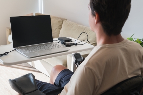 disabled man using computer, with special adaptive devices - Australian Stock Image