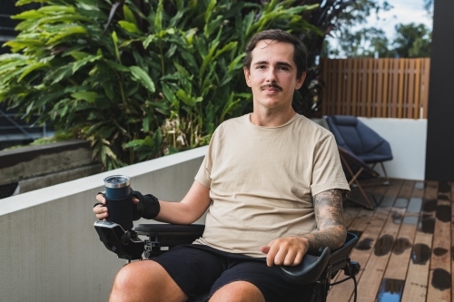 disabled man with custom made drinking cup - Australian Stock Image