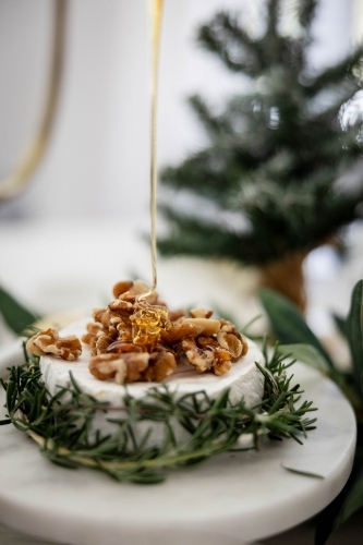 Dish of Camembert with rosemary and walnuts on decorated Christmas table - Australian Stock Image
