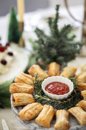 Dish of savoury pastries on Christmas-decorated table - Australian Stock Image