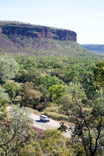 Distant car driving along road in bushland