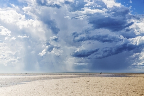Distant people on beach with storm approaching - Australian Stock Image