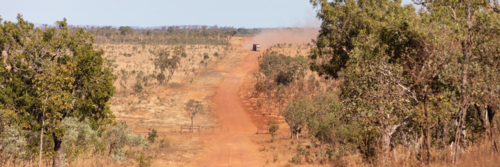 Distant road train on a dusty NT red dirt track - Australian Stock Image