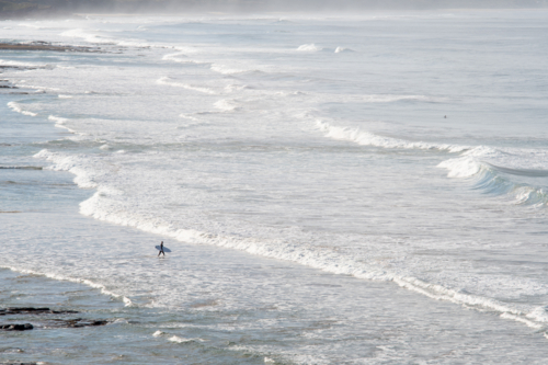 Distant surfer entering the surf - Australian Stock Image