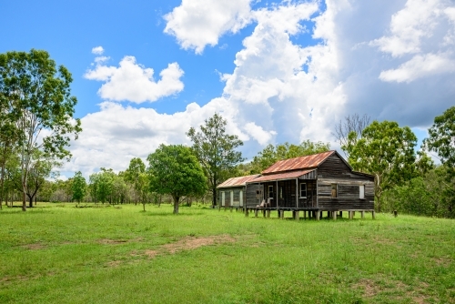 Disused wooden homestead surrounded by grazing field and dramatic stormy sky - Australian Stock Image