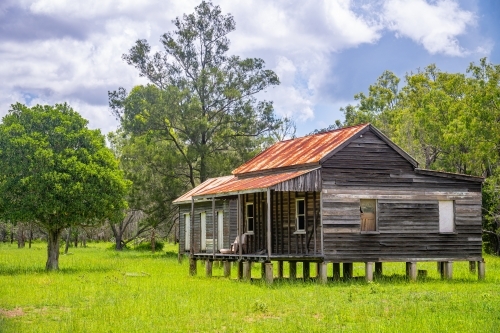 Disused wooden homestead surrounded by grazing field and dramatic stormy sky - Australian Stock Image