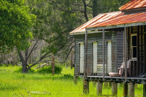 Disused wooden homestead surrounded by grazing field and dramatic stormy sky in