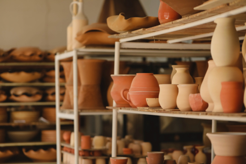 Diverse handcrafted pottery on rustic shelves in a workshop - Australian Stock Image
