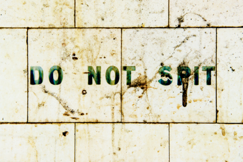 Do not spit sign painted on dirty tiled wall. - Australian Stock Image