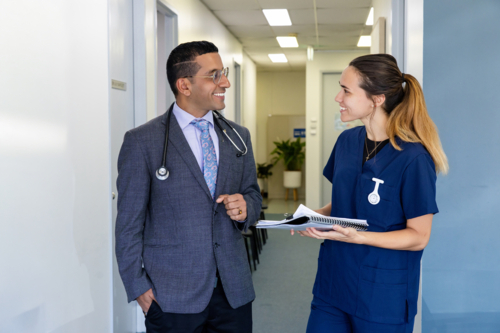 Doctor and nurse smiling and talking in office - Australian Stock Image