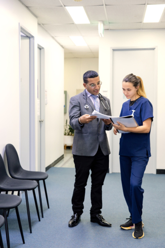 Doctor and nurse talking while walking on the hallway - Australian Stock Image