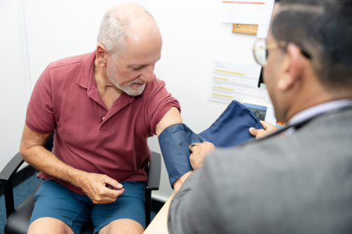 Doctor checking senior mans blood pressure - Australian Stock Image