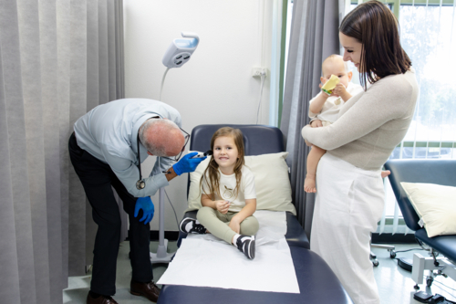 Doctor checking young girls ear with otoscope - Australian Stock Image