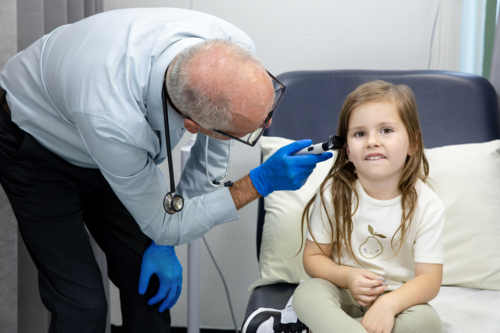 Doctor checking young girls ear with otoscope - Australian Stock Image