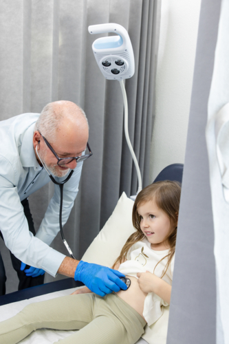Doctor checking young girls tummy with stethoscope - Australian Stock Image