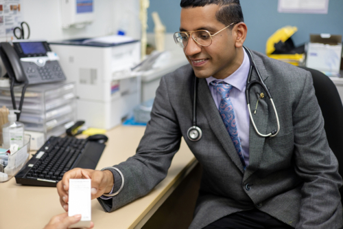 Doctor handing prescription medicine to female patient - Australian Stock Image