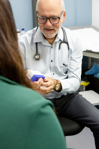 Doctor holding a medicine box showing it to patients - Australian Stock Image