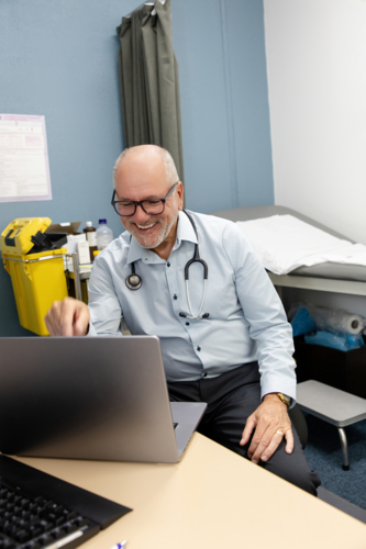 Doctor in office working at laptop - Australian Stock Image
