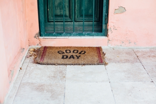 Doormat in front of green door on pink house - Australian Stock Image