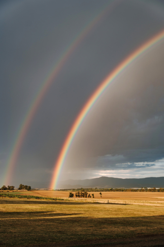 Double rainbow arching over a vast farmland - Australian Stock Image