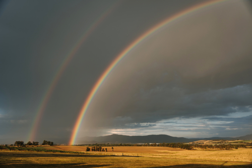 Double rainbow arching over a vast farmland - Australian Stock Image