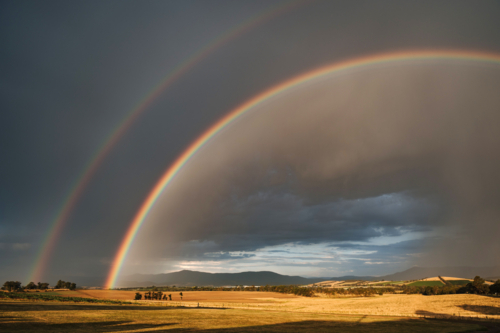 Double rainbow arching over a vast farmland - Australian Stock Image