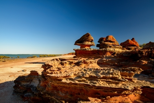 Dramatic and unusual orange rock formations on a bayside beach - Australian Stock Image