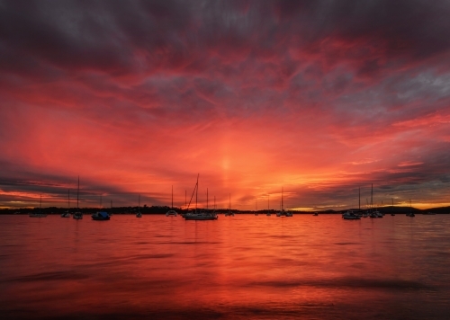 Dramatic red sunset behind yachts moored at Roy Wood Reserve, Port Stephens