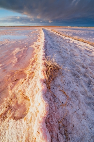 Dramatic side lightning hitting a rusted corrugated fence buried in salt lake - Australian Stock Image