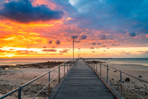 Dramatic sunset above Moonta Bay Jetty with people walking along,  Copper Coast, Yorke Peninsula - Australian Stock Image