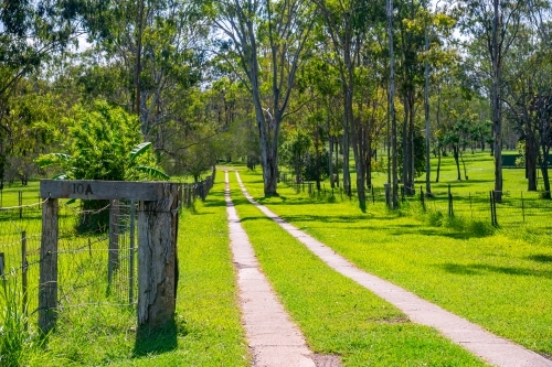 Driveway to house with vibrant green grass and wooden fence and house number - Australian Stock Image