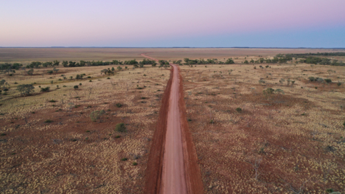 Drone shot of a dirt road going through creek and plain - Australian Stock Image