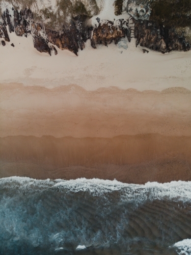 Drone shot of waves crashing on a beach from above