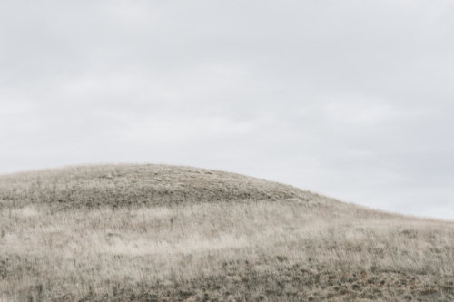 Dry, grassy hill with grey sky - Australian Stock Image