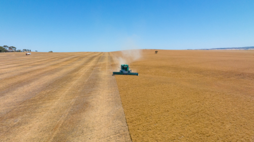 Dry-land farming machinery harvesting crop in farm paddock - Australian Stock Image