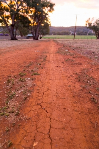 Dry red cracked earth path on a rural property at dusk - Australian Stock Image