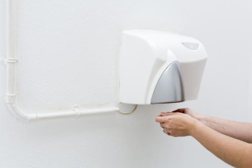 Drying hands at an outdoor public hand dryer. - Australian Stock Image