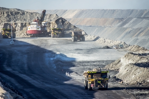 Dump trucks filling up with overburden and carting it through open cut coal mine - Australian Stock Image