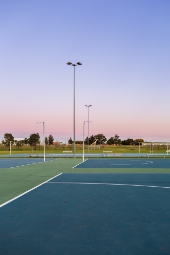 Dusk sky behind empty netball courts in sports park - Australian Stock Image