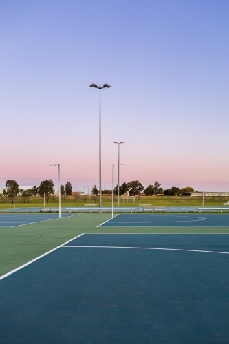 Dusk sky behind empty netball courts in sports park