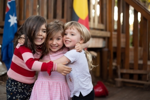 Early education, three girls hugging - Australian Stock Image