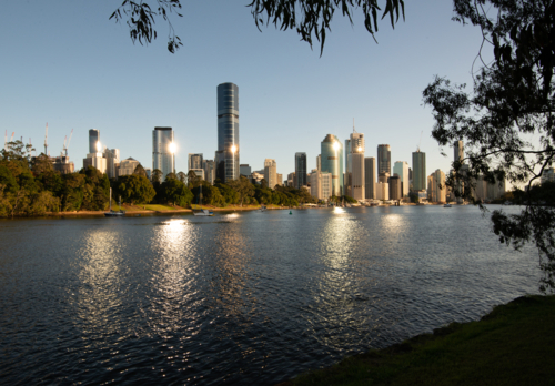Early morning view across river to city with sunbursts and reflections - Australian Stock Image