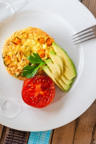 Egg omelet with avocado slices and grilled tomato on a plate. - Australian Stock Image