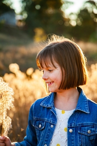 Eight year old girl outside backlit by golden sunset light